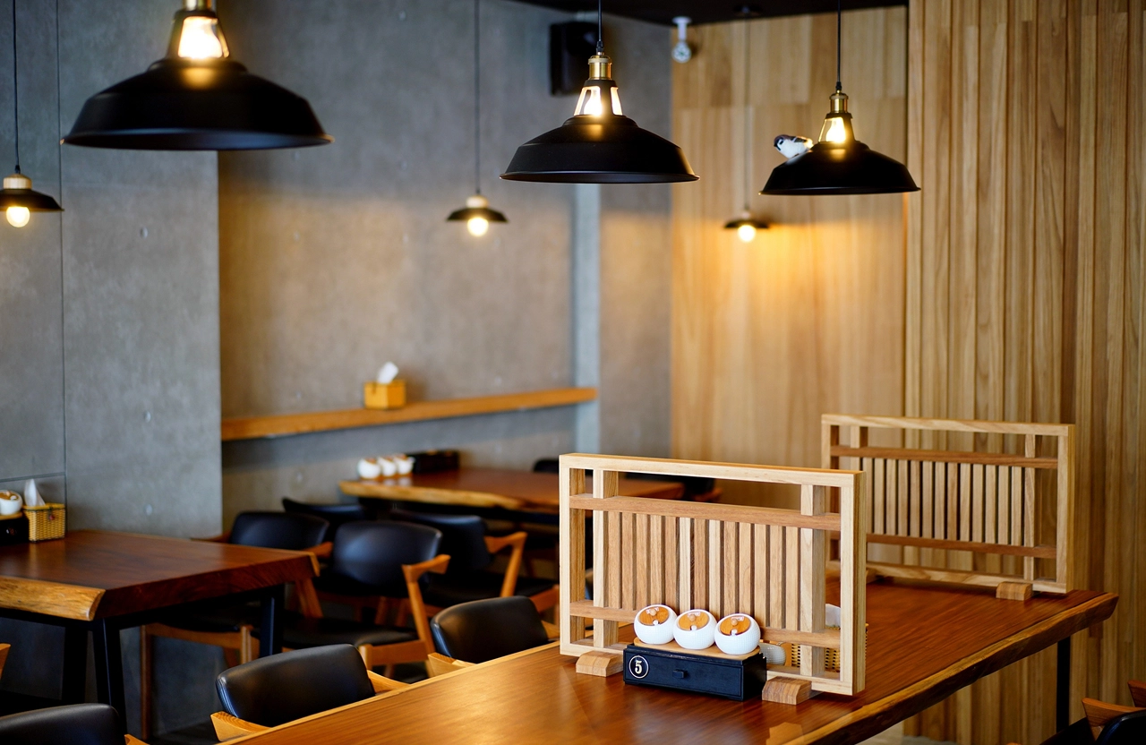 餐廳桌椅家具規劃：工業風黑色吊燈搭配實木長桌，清水模牆面營造質感用餐氛圍，適合商業空間設計參考。