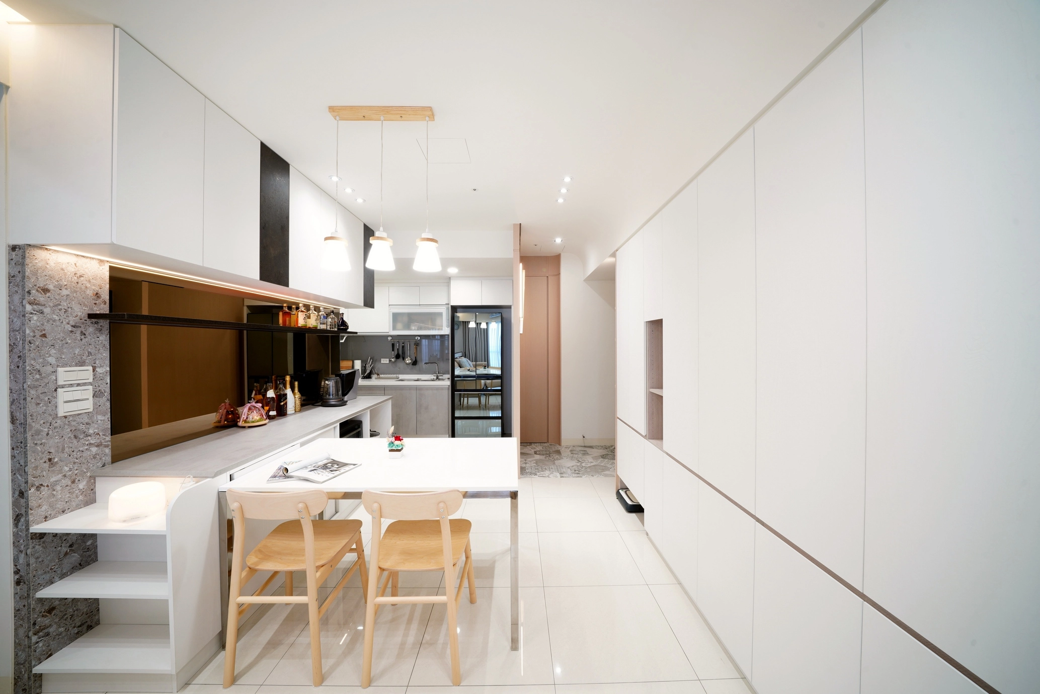 德盈設計餐廚空間:白色系統高櫃整合餐桌,運用開放式層架與燈光配置,創造俐落開闊視野。