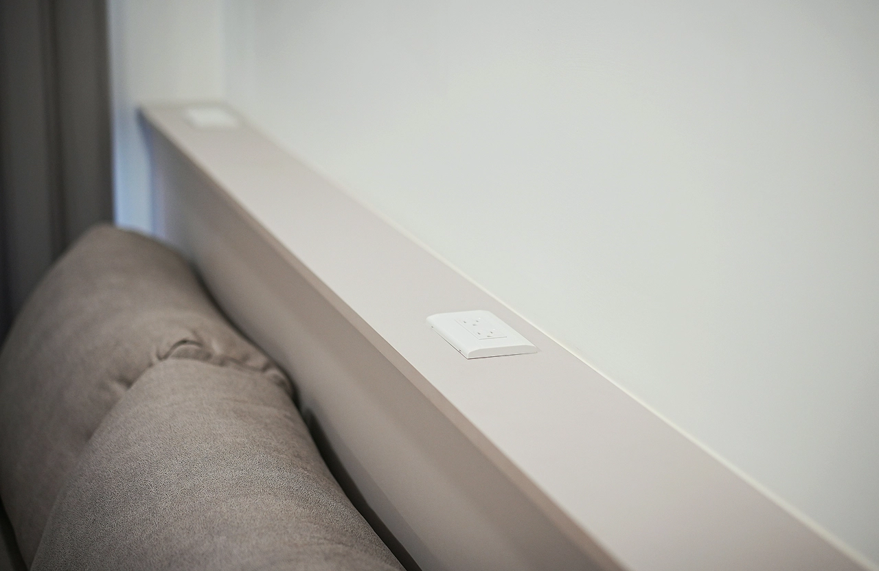 客廳收納機能細節：沙發背後設置長型置物平台與內嵌插座，貼心設計滿足手機充電與雜物收納需求。