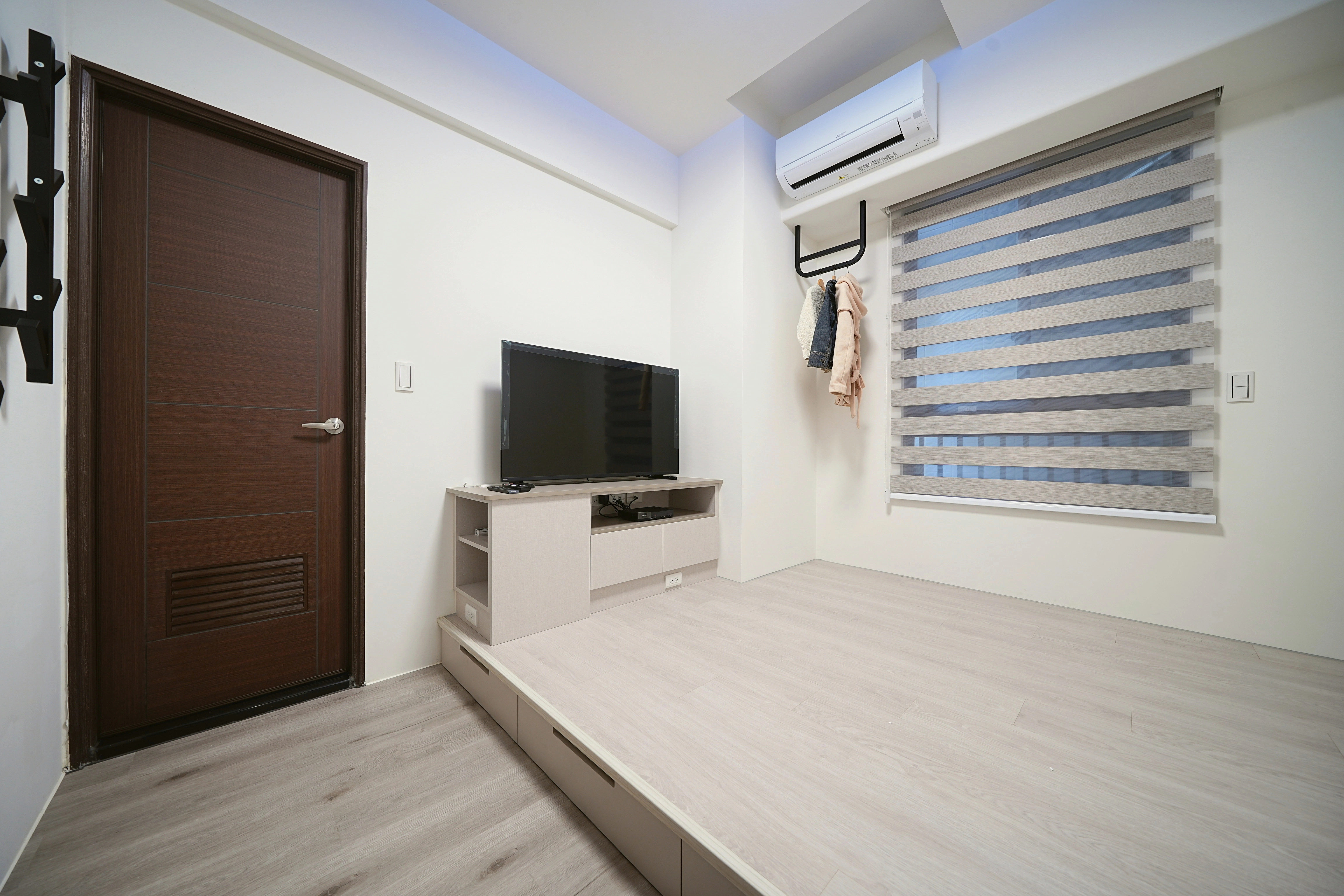 德盈室內設計:臥室架高地板設計,結合客製化電視收納櫃與黑鐵吊衣架,極大化小坪數居家儲物空間。