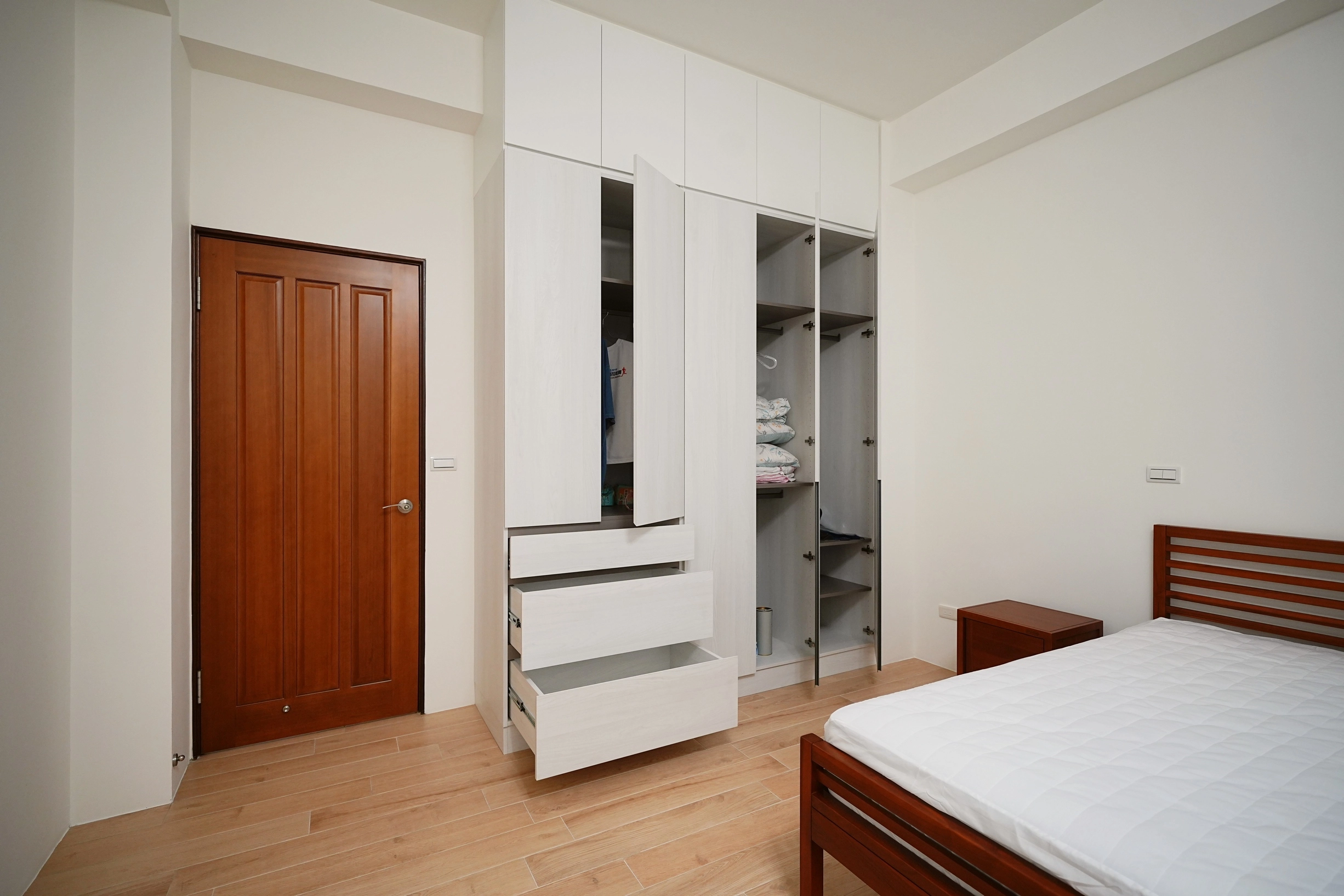 德盈空間規劃:系統櫃選用霧面質感材質,與暖色木地板相互呼應,堆疊出沉穩且精緻的臥室美學。