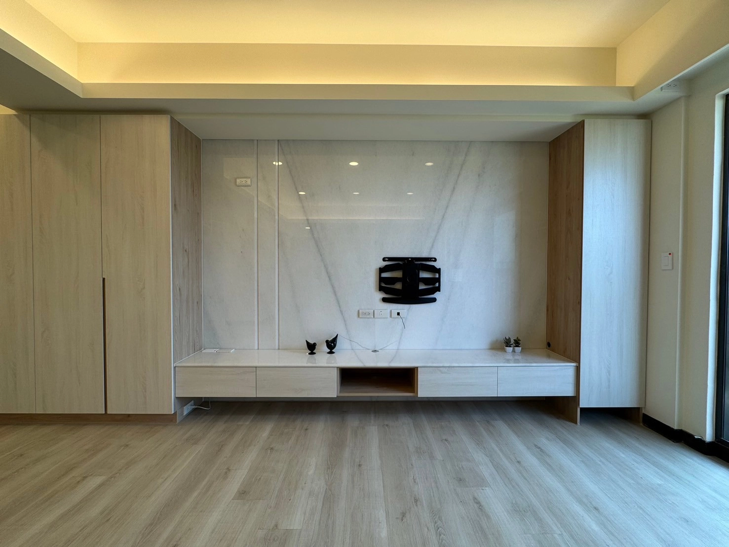 德盈室內設計:大理石電視牆下方搭配燈條,透過懸空設計與洗牆光影,營造空間輕盈感與高級質感。