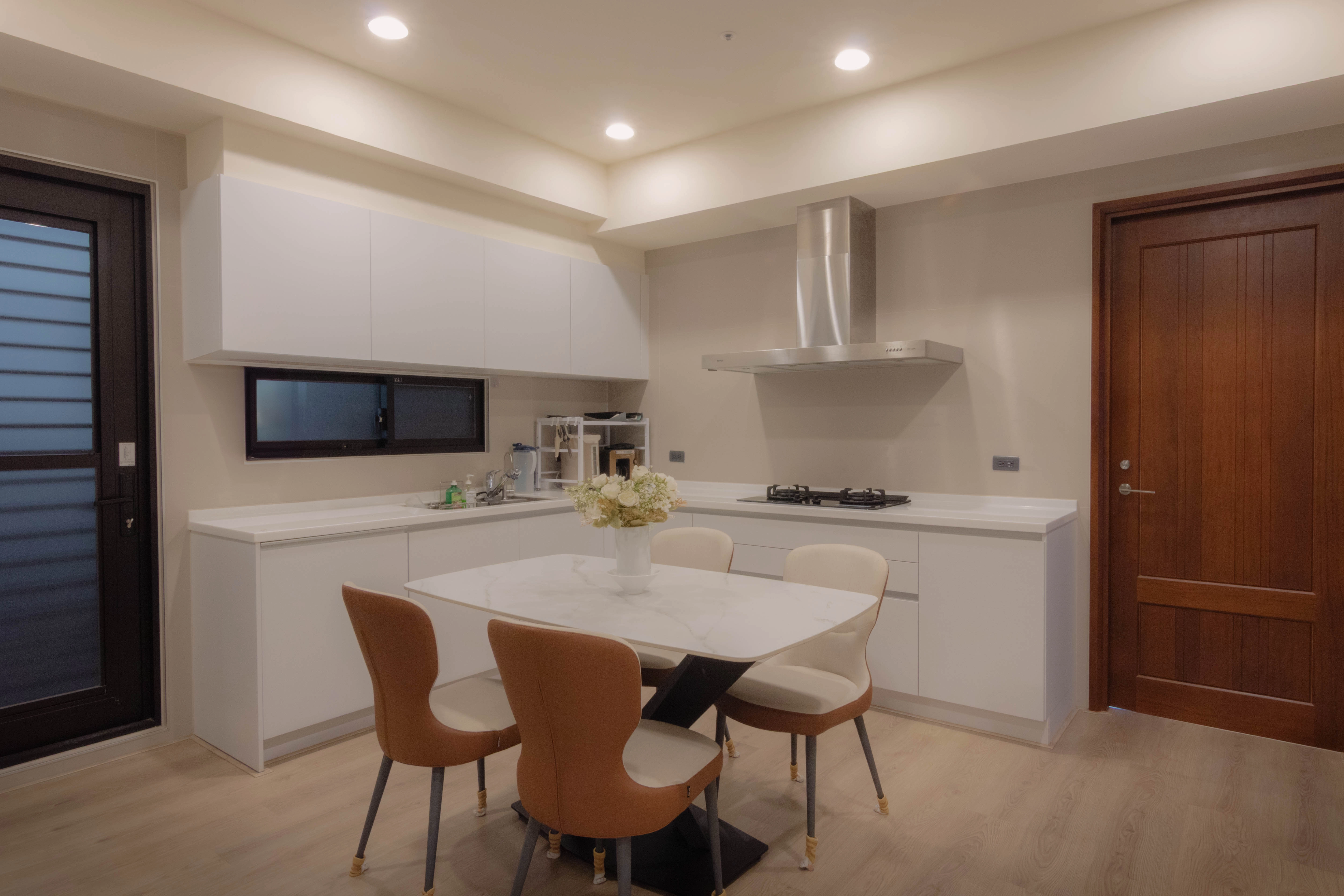 德盈設計餐廚實景:純白石紋中島與木質餐桌整合,打造現代感開放式廚房空間。