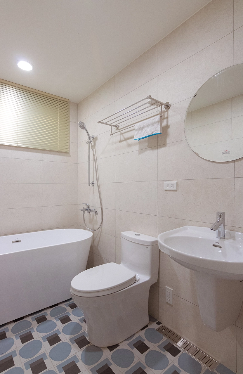 浴室地板採用復古幾何藍調花磚，結合簡約獨立浴缸設計，透過大膽地磚配色為衛浴空間增添視覺亮點。