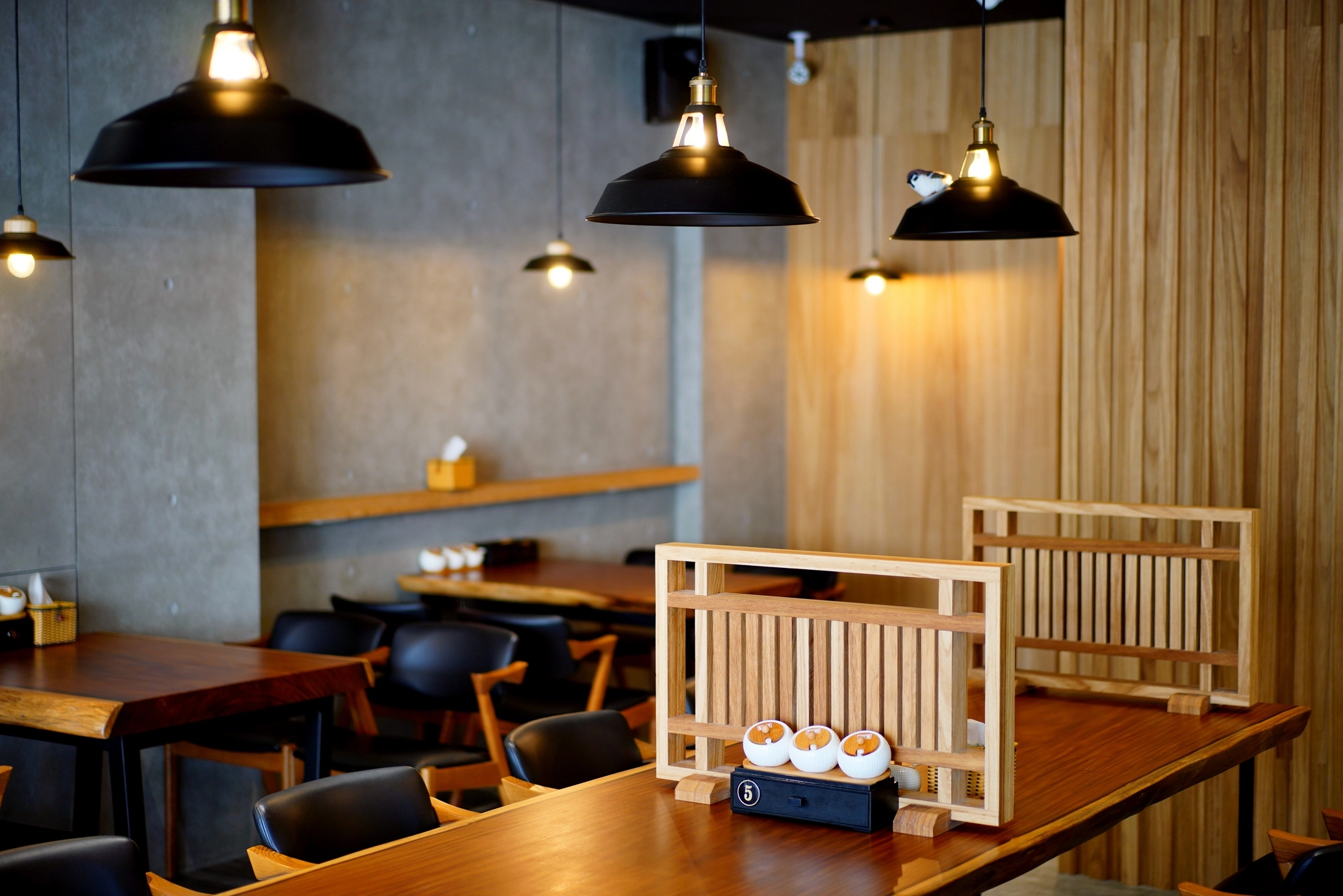 餐廳桌椅家具規劃:工業風黑色吊燈搭配實木長桌,清水模牆面營造質感用餐氛圍,適合商業空間設計參考。