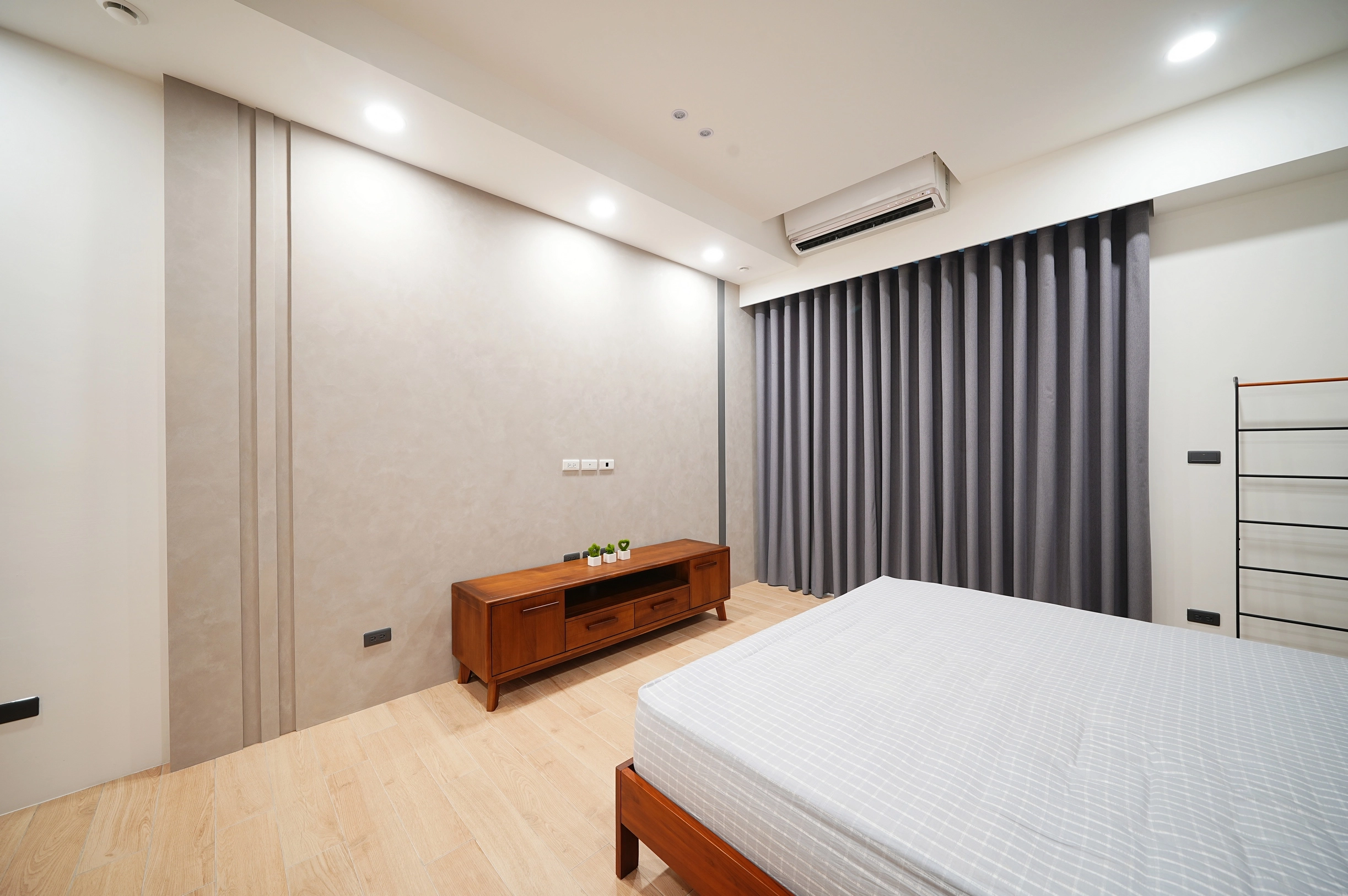 德盈空間規劃:客製化藝術塗料電視牆,細膩手作紋理搭配懸空式電視櫃,展現現代簡約的主臥美學。