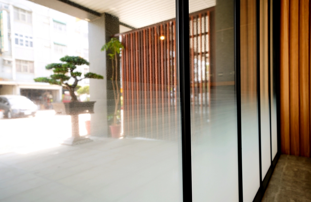 德盈室內設計：餐飲場域入口採用漸層磨砂玻璃門，結合戶外禪意造景，打造專業且具隱私感的門面設計。