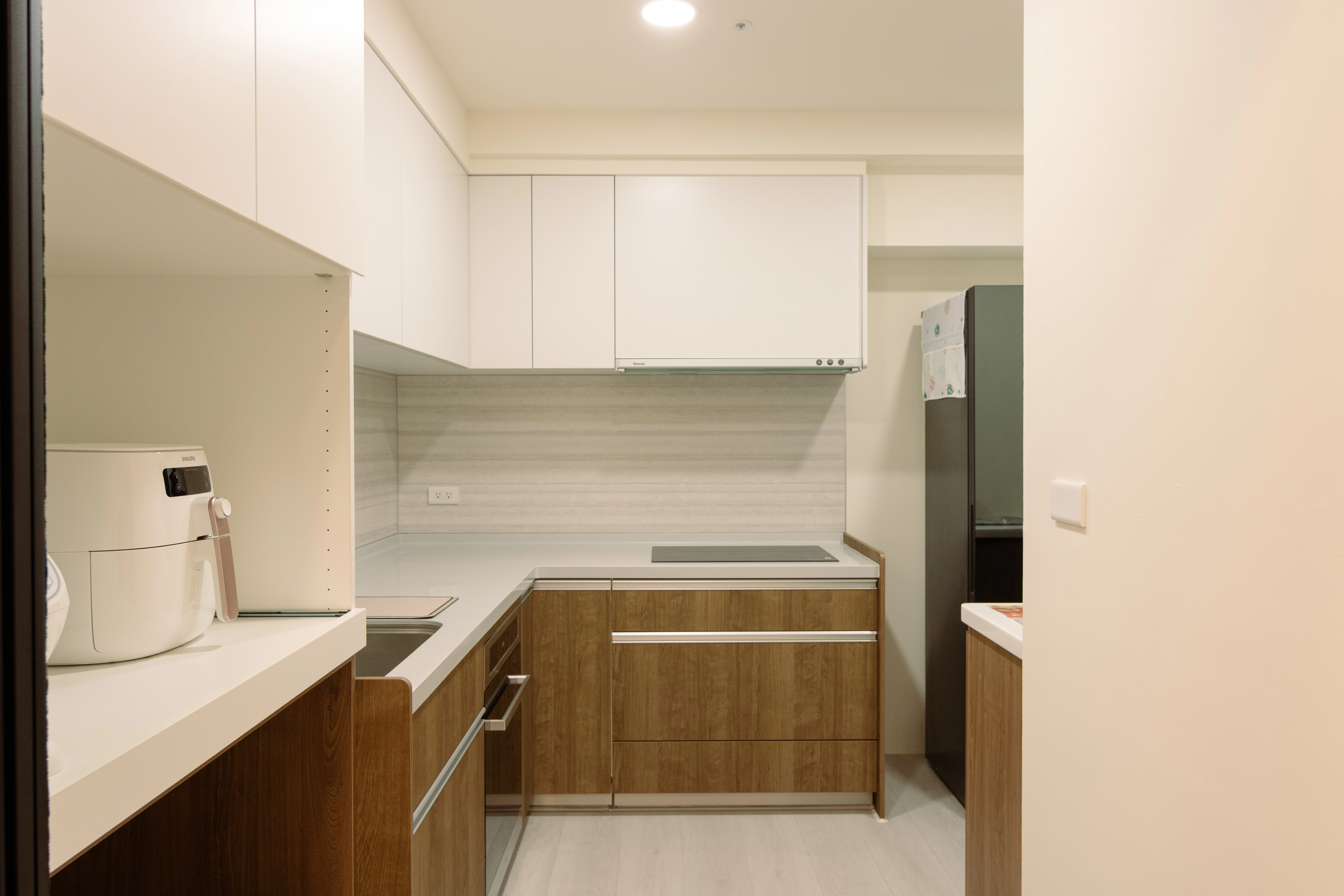 系統廚具搭配推拉盤設計。上白下木質配色，搭配開放層板，實用簡潔。