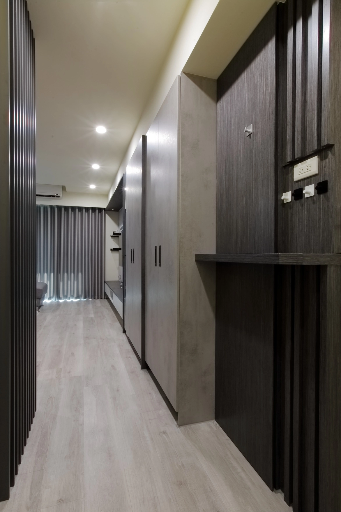 德盈設計玄關實景：深色木質屏風結合灰系系統鞋櫃，營造沈穩進門視野。