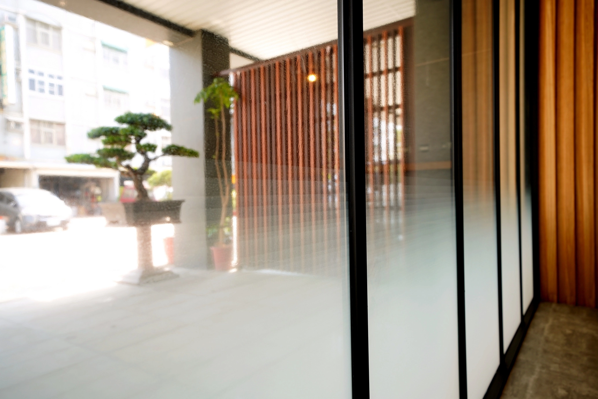 德盈室內設計:餐飲場域入口採用漸層磨砂玻璃門,結合戶外禪意造景,打造專業且具隱私感的門面設計。