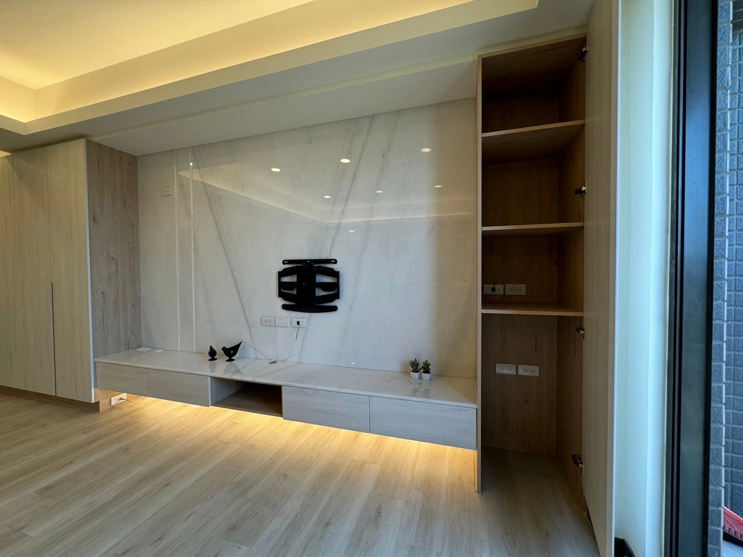 德盈空間規劃:於電視牆旁開門系統櫃,巧妙整合收納機能,讓居家空間維持整潔且流暢的視覺美感。