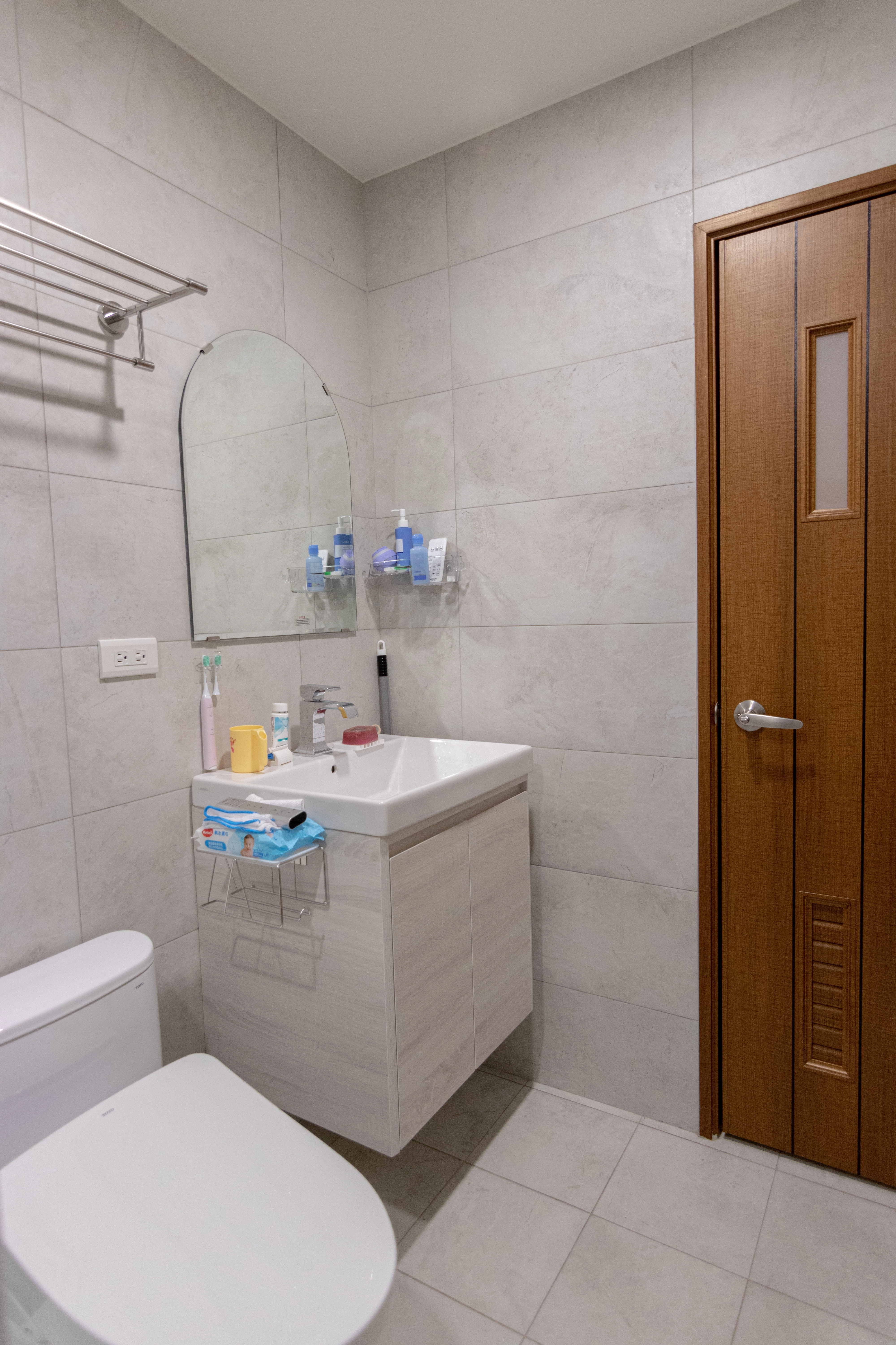 浴室系統化收納規劃，懸空式洗手台櫃體搭配拱型浴鏡，客製化衛浴家具提升居家生活質感與實用性。