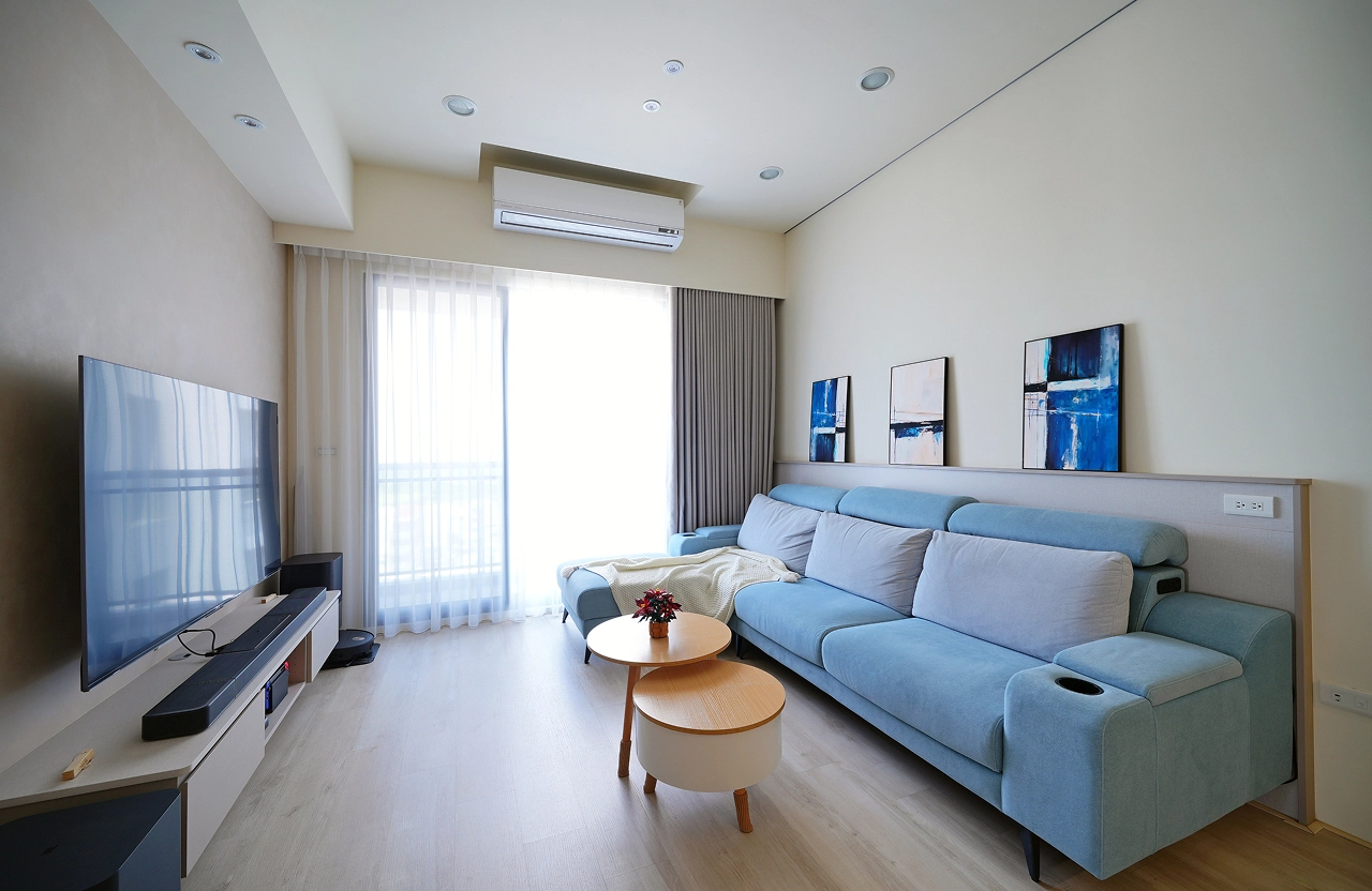 德盈室內設計客廳裝修：藍色沙發搭配木質地板，大面採光營造明亮寬敞家宅感。