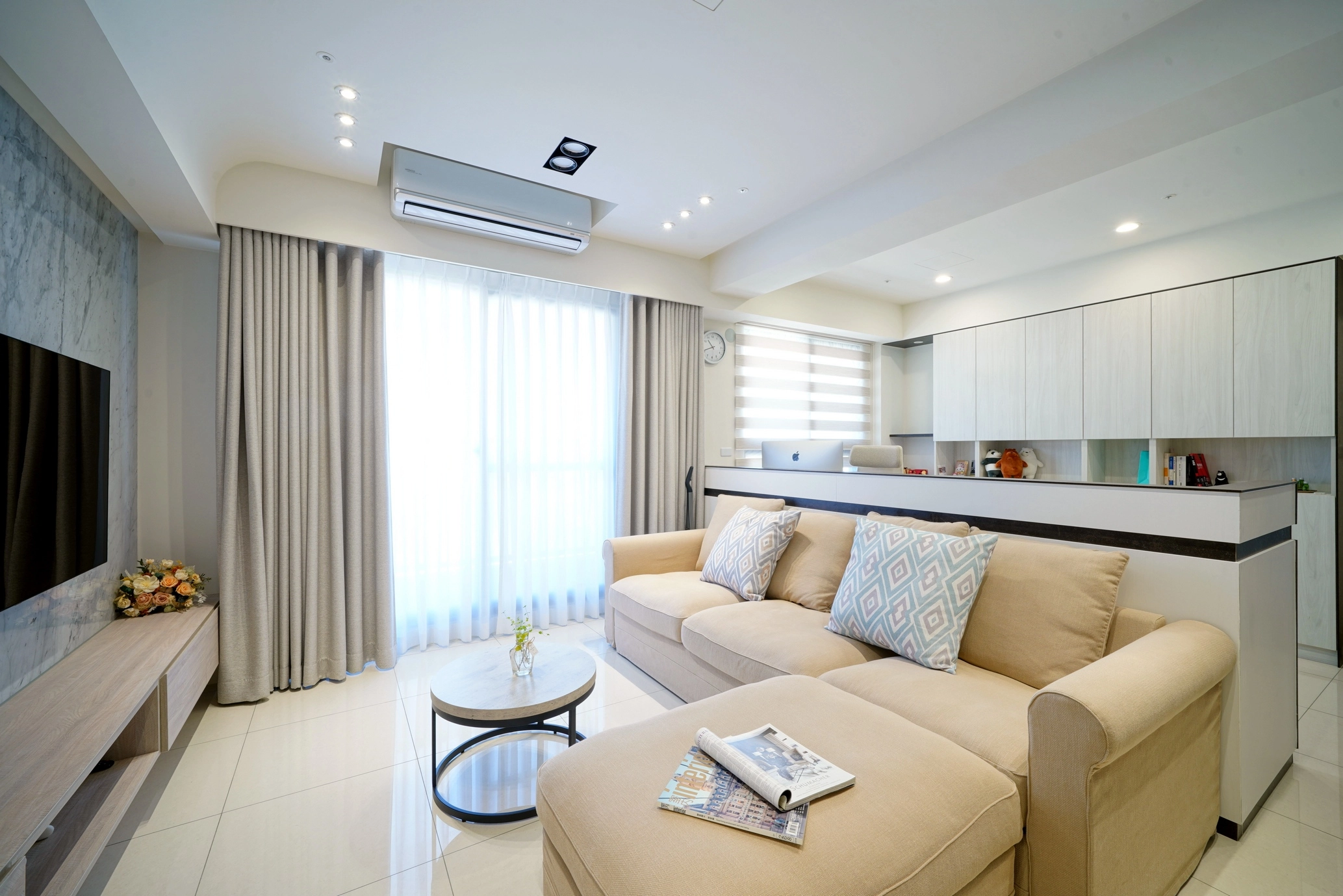 德盈客廳案例實景:米色系沙發結合後方半高牆書櫃,兼具收納與視覺通透。