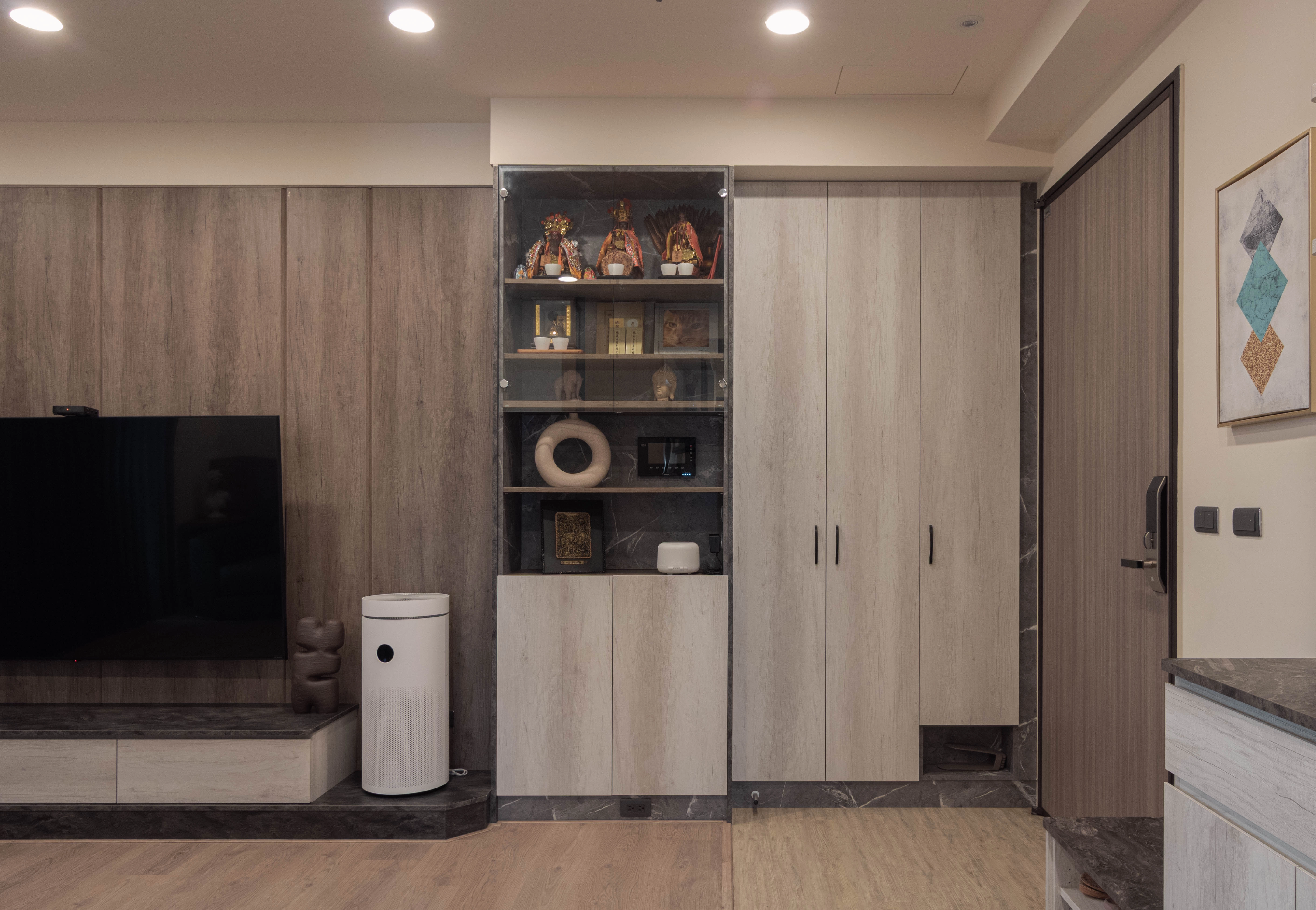 玄關系統開門高櫃搭玻璃門片。客廳沙發木作半高牆區隔,增加視覺層次。