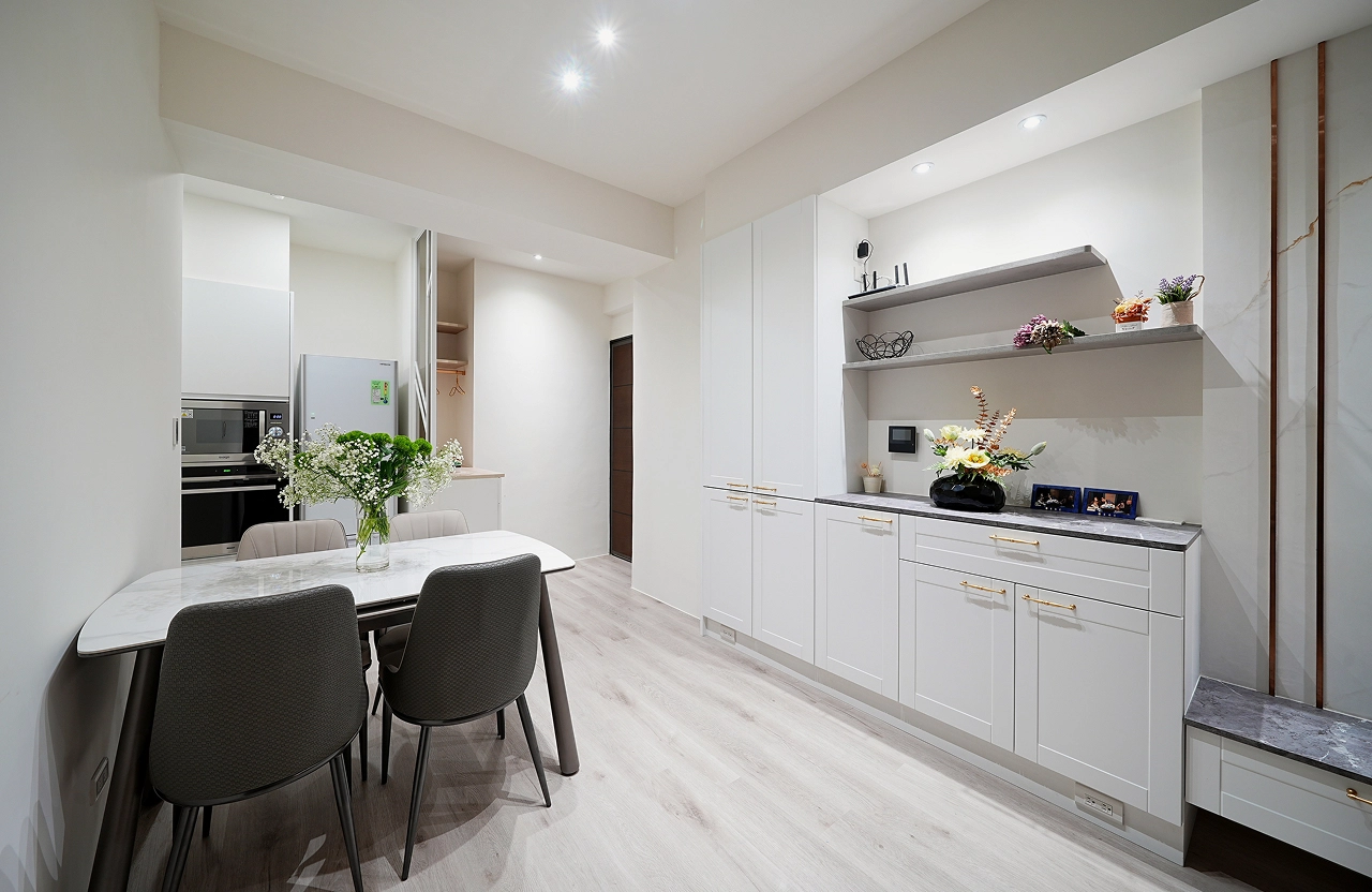 歐式門片廚房系統櫃： 純白線板搭配金屬把手，營造典雅餐飲空間。