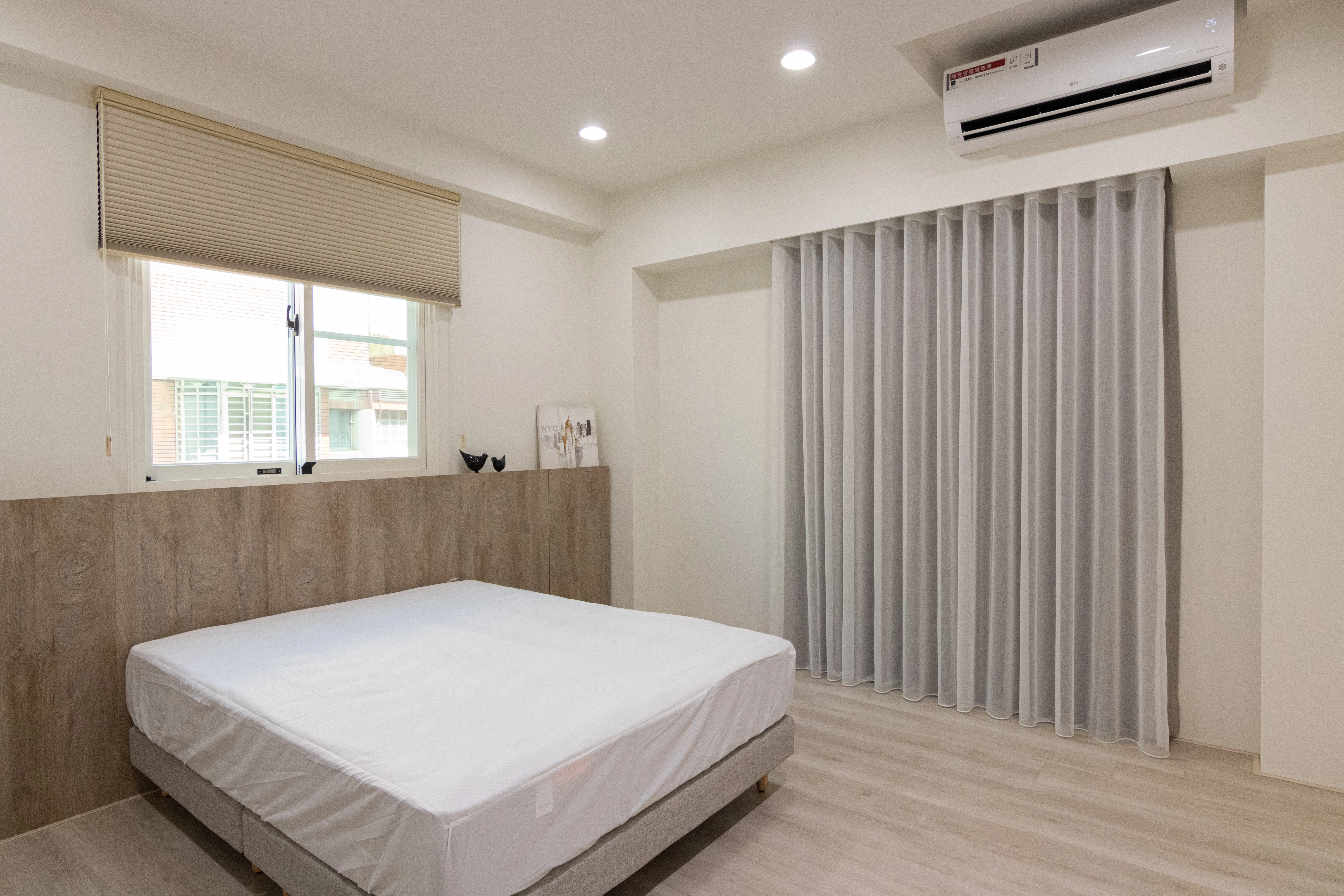 北歐風臥室設計採用淺木色系統床頭背牆,搭配超耐磨木地板與落地窗簾,營造自然舒適的居家裝潢氛圍。