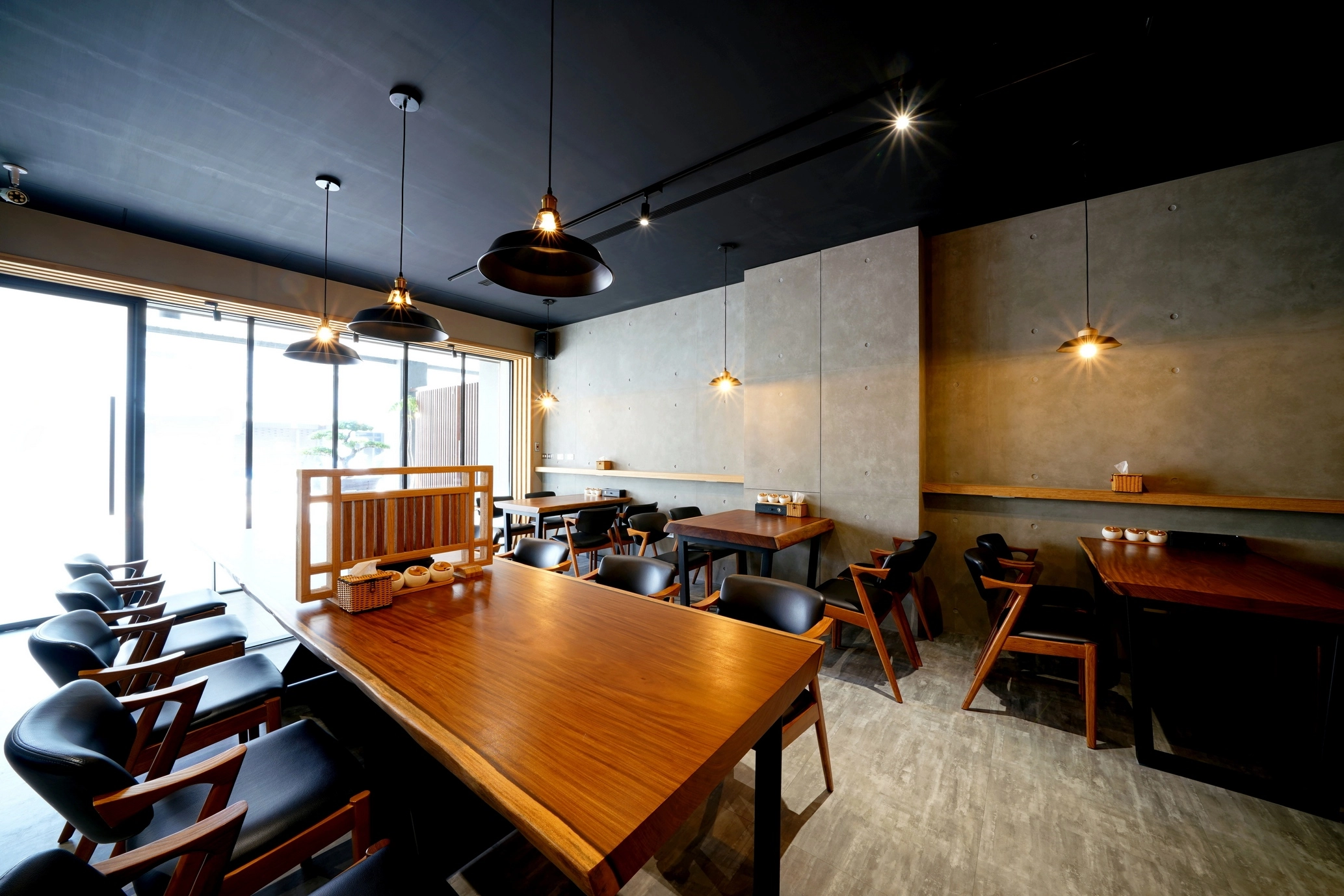 商業空間裝潢案例:餐廳落地窗引進自然採光,黑色工業風燈飾點亮實木餐桌,呈現簡約沉穩的日式設計氛圍。