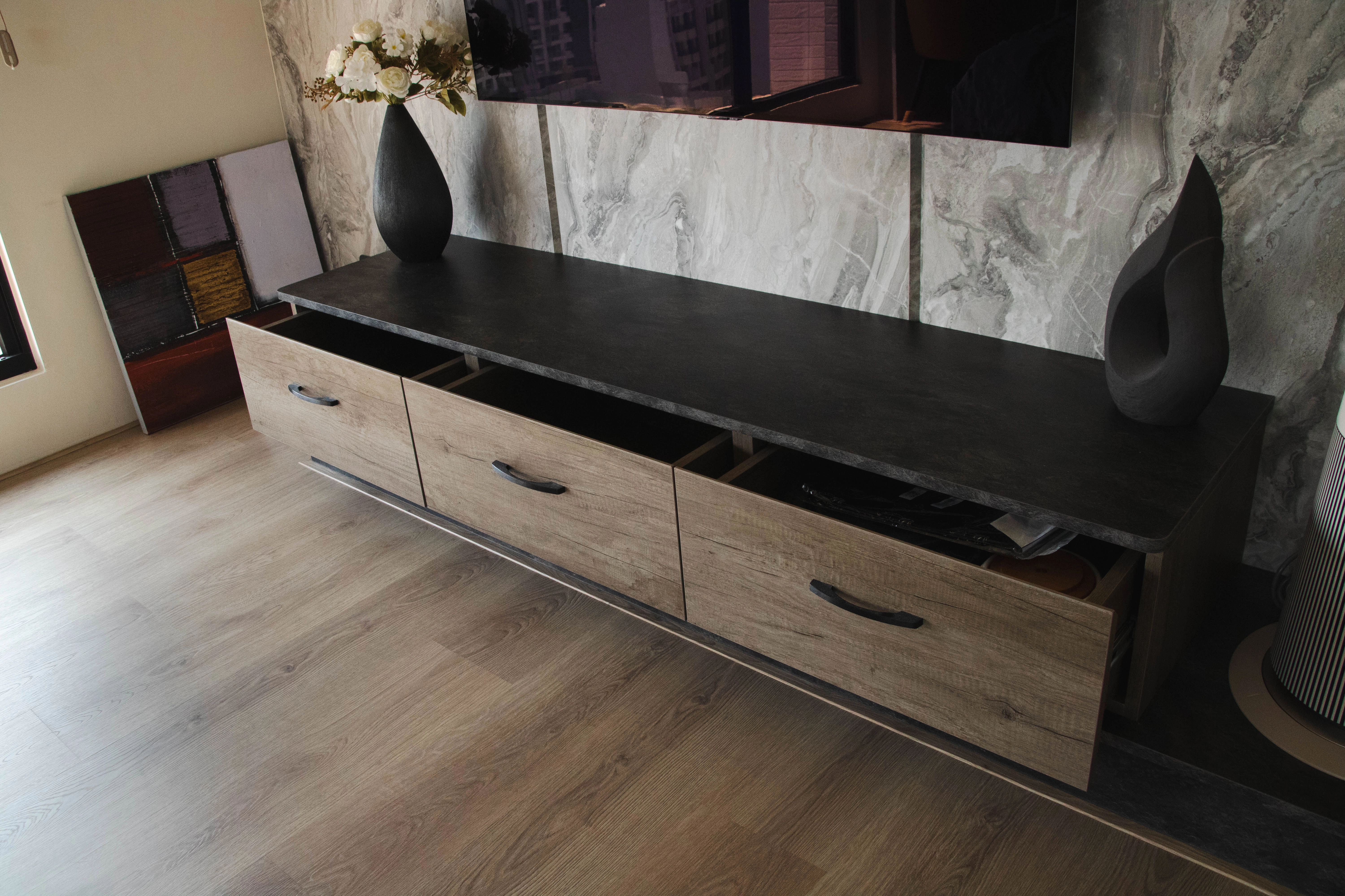 德盈室內設計懸吊式電視系統櫃案例:沉穩木質抽屜搭配石紋壁面,底部懸空設計便於清潔,打造現代極簡客廳質感。