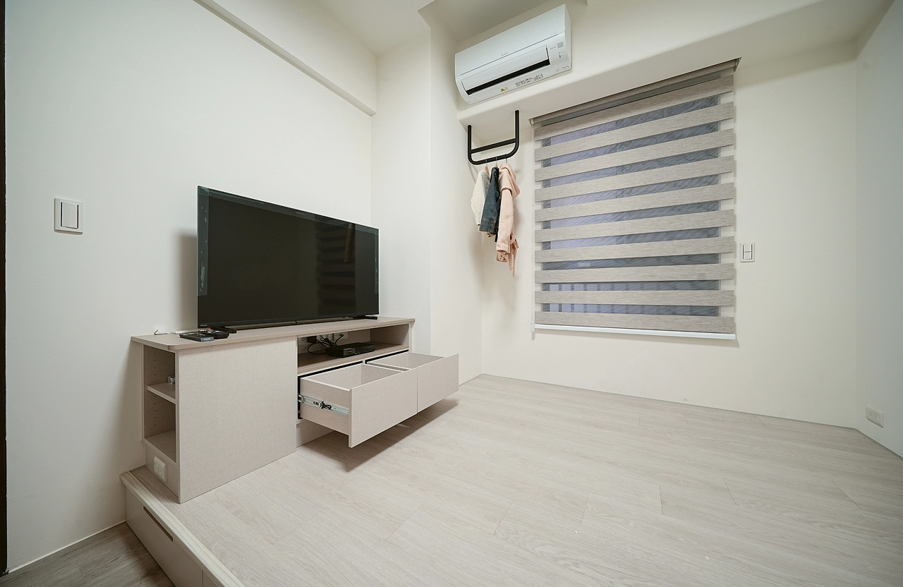 小坪數收納規劃：臥室系統電視櫃配備滑軌抽屜，架高木地板增加大容量收納，打造簡約清爽的機能睡房。