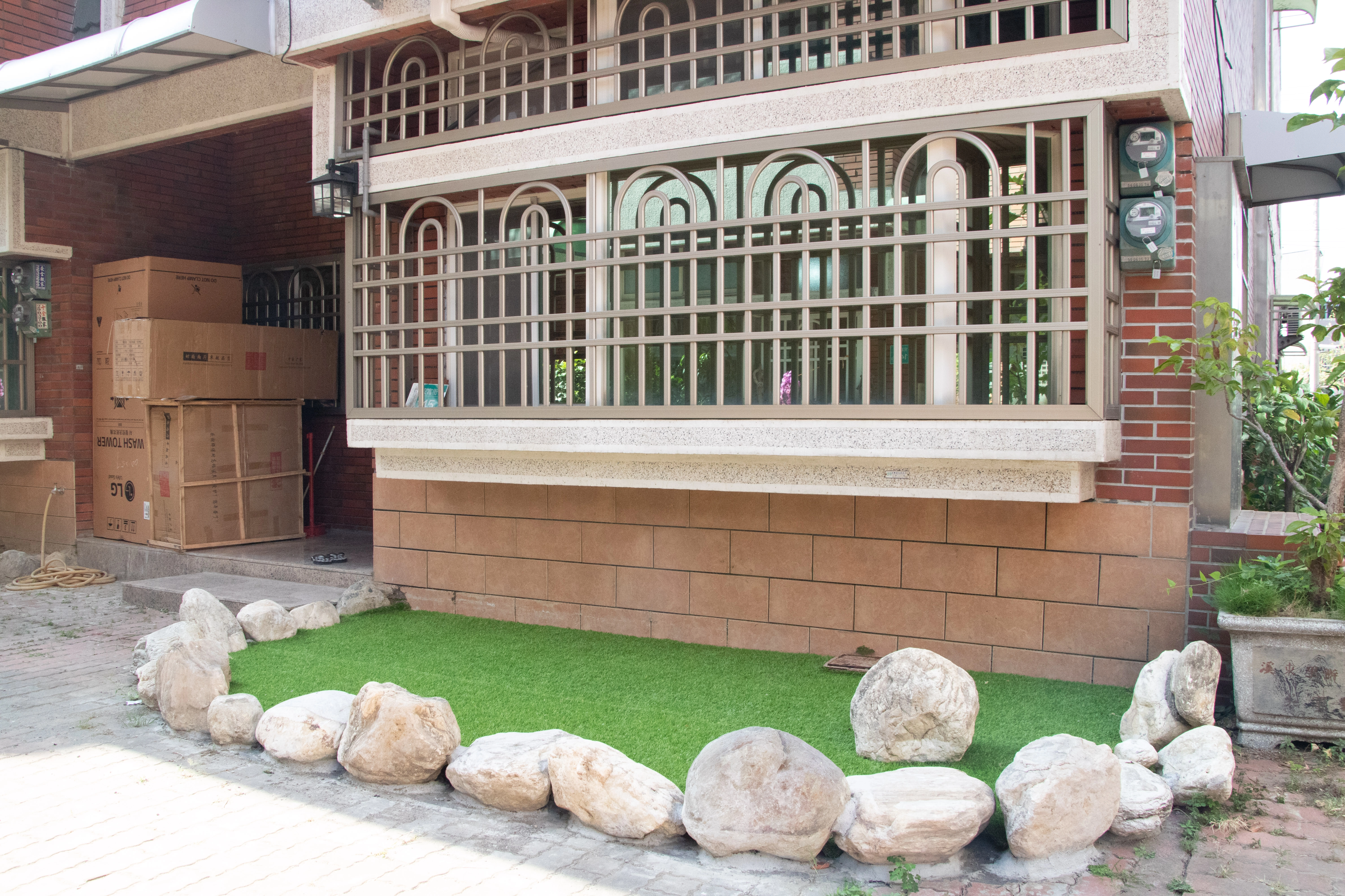 透天住宅戶外花圃美化方案,結合人工草皮、白鵝卵石與景觀植栽規劃,打造低維護且具質感的居家園藝端景。