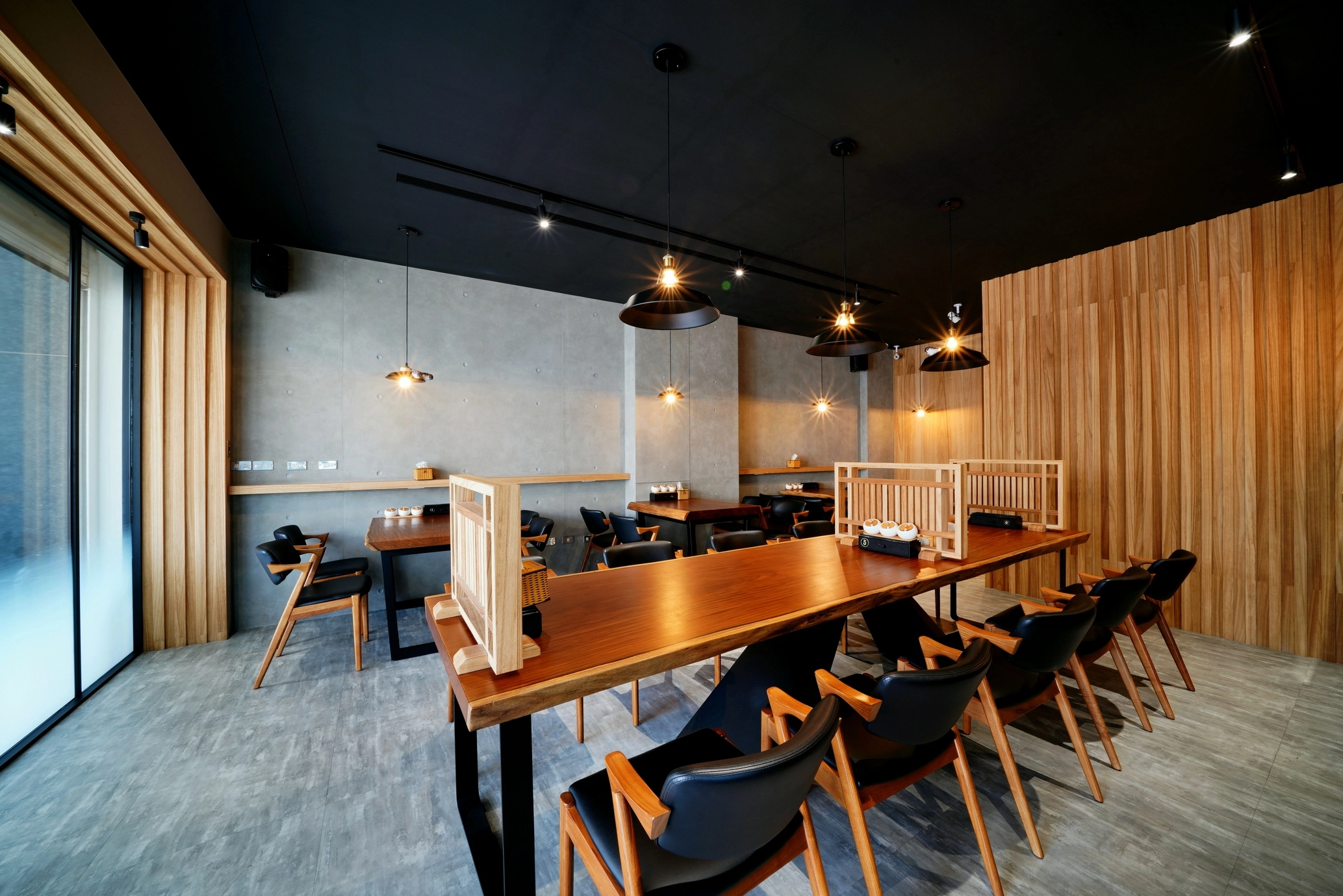 德盈室內設計:日式工業風餐廳規劃,清水模牆面搭配大型實木長桌與木質格柵,打造質感商業用餐空間。