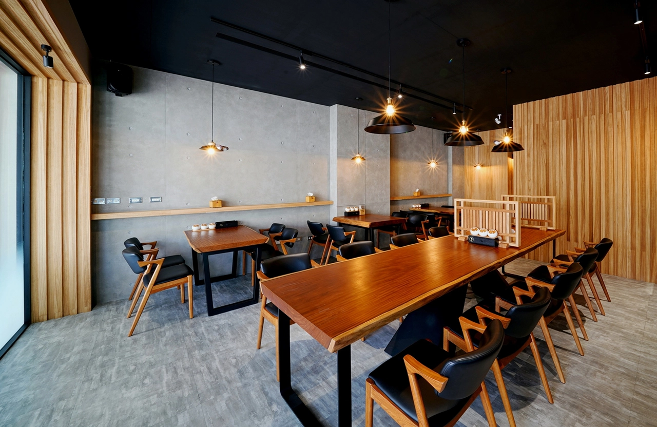 德盈室內設計：日式工業風餐廳規劃，清水模牆面搭配大型實木長桌與木質格柵，打造質感商業用餐空間。