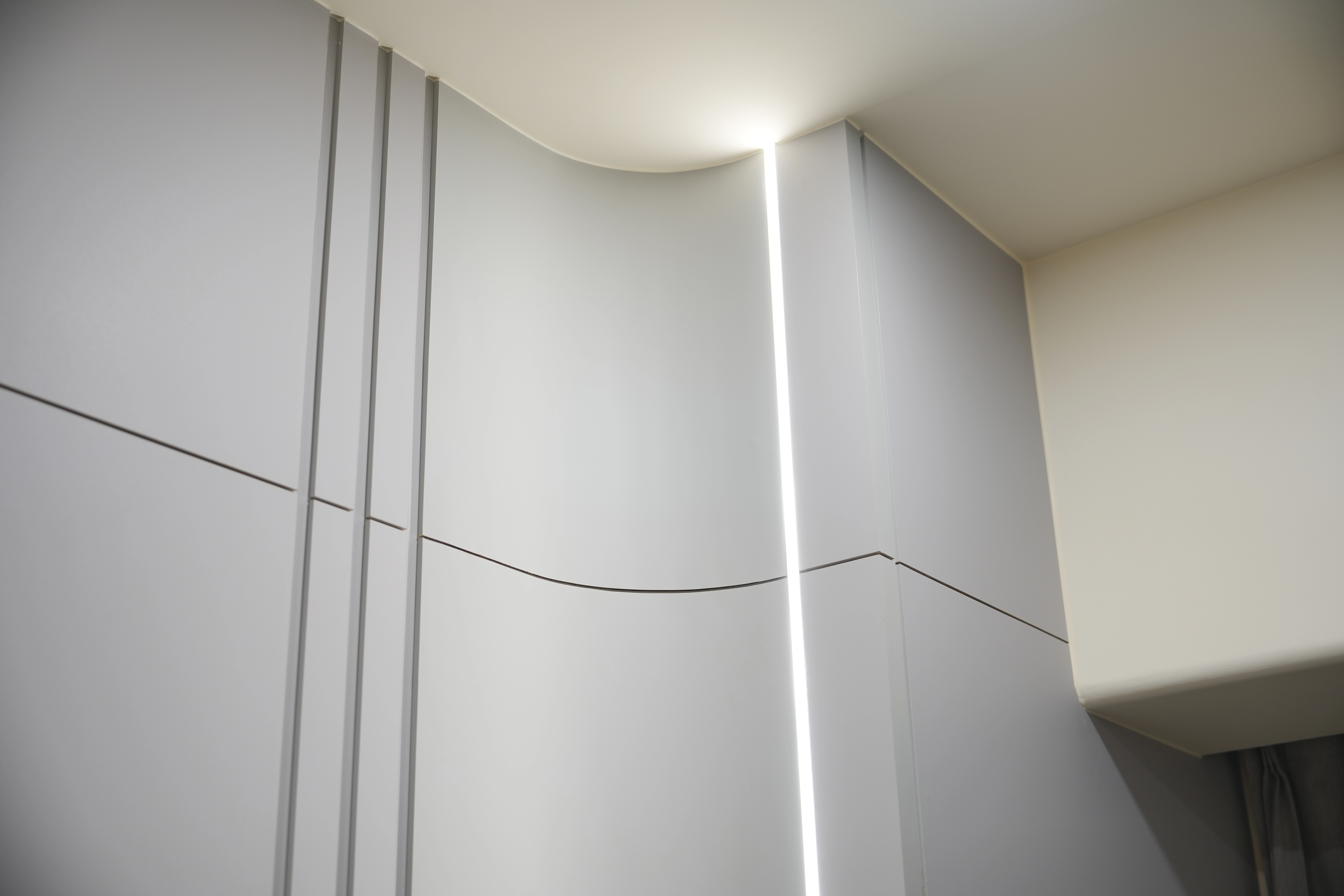 德盈室內設計:內嵌燈條結合弧形牆面工藝,展現細膩的線性燈光美學細節。