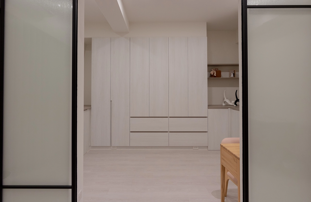 簡約白色木紋系統衣櫃結合現代室內設計，頂天立地設計增加收納空間，營造清爽整潔的居家視覺美感。