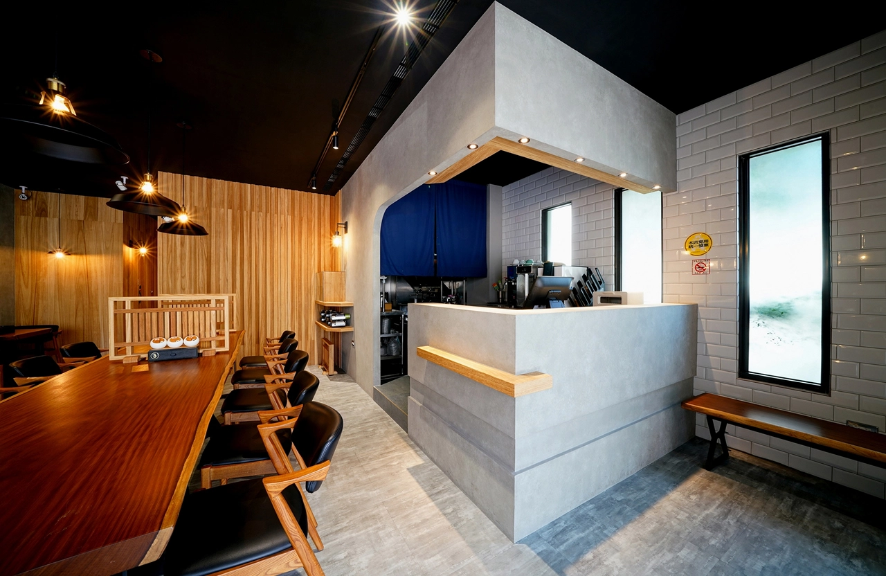 德盈室內設計：日式風格餐廳裝潢，清水模櫃檯結合木質格柵牆面，打造具專業感的餐飲商業空間。