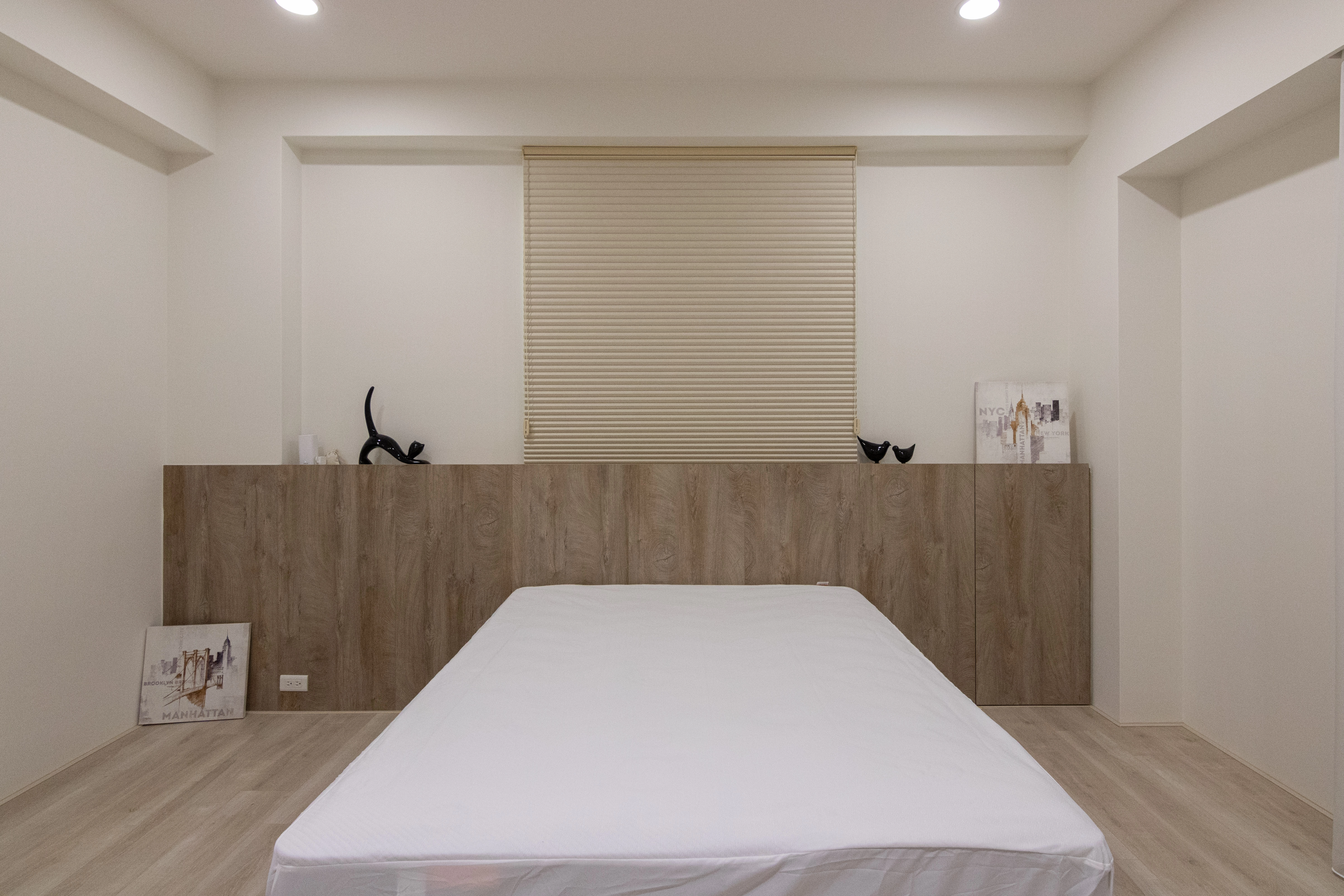 客製化木質床頭背牆具備收納功能,簡約設計化解壓樑問題,完美結合系統家具美學與實用臥室規劃。