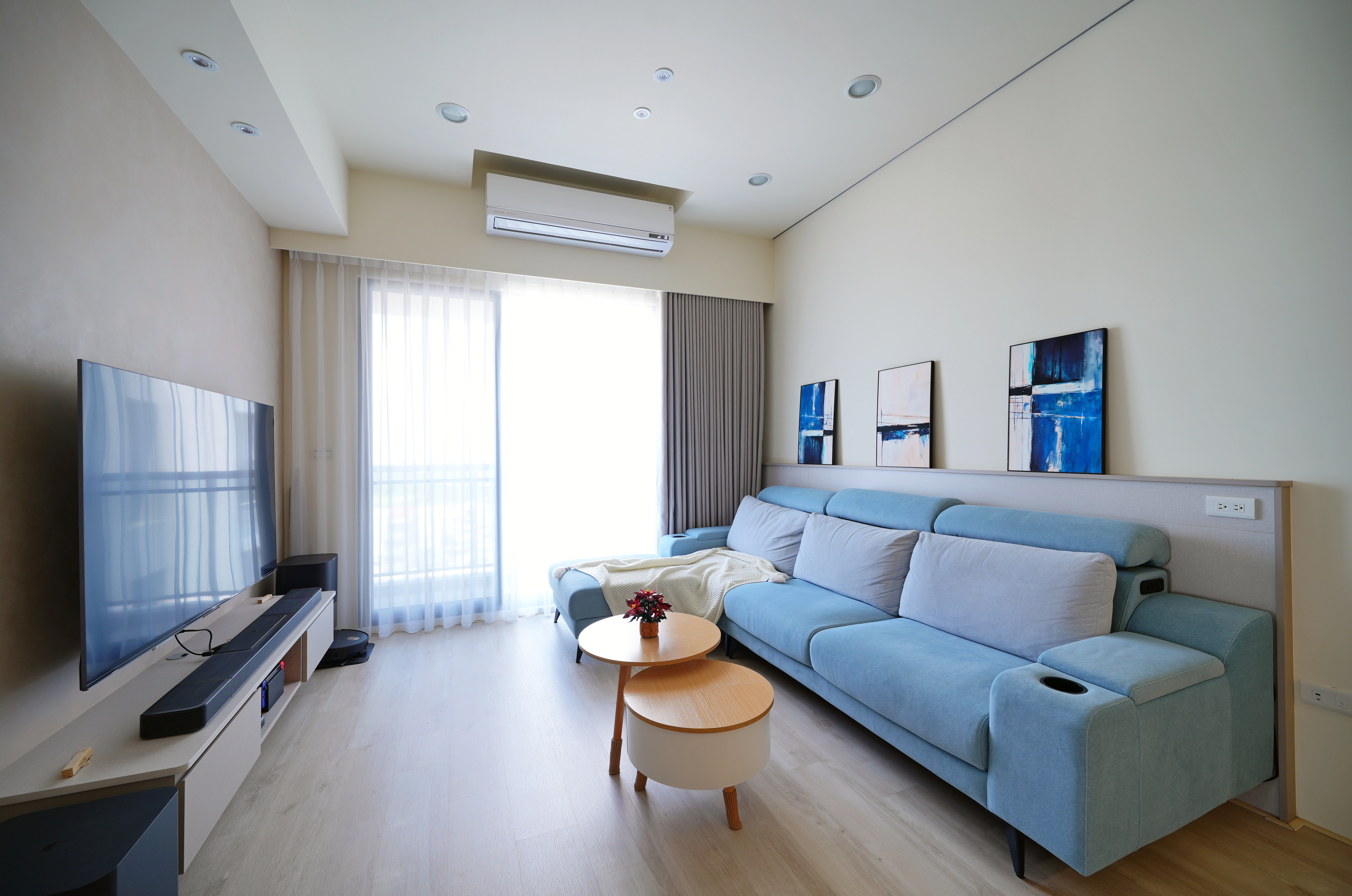 德盈室內設計客廳裝修:藍色沙發搭配木質地板,大面採光營造明亮寬敞家宅感。