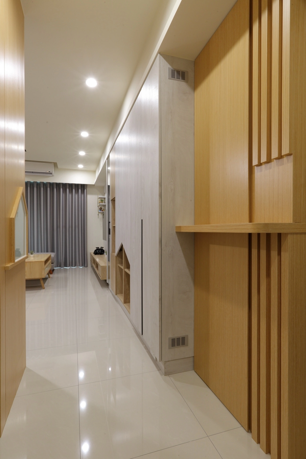 走廊收納規劃一體式系統家具，結合趣味屋型挖空設計與格柵線條，在維持簡潔立面的同時展現豐富的空間層次感。