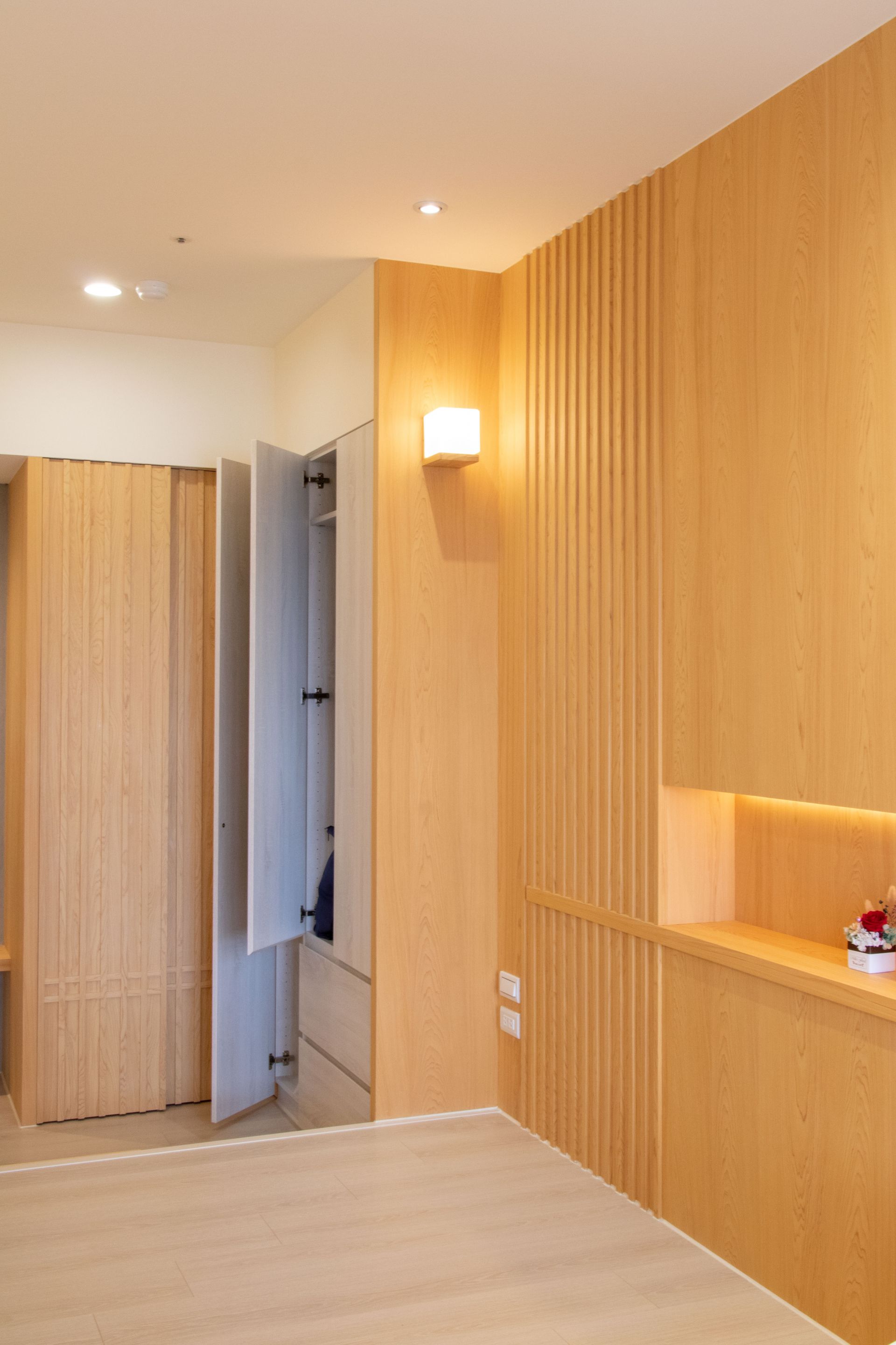 淺色木質營造溫馨感。木作格柵造型門片與隱藏門，讓空間動線更流暢。