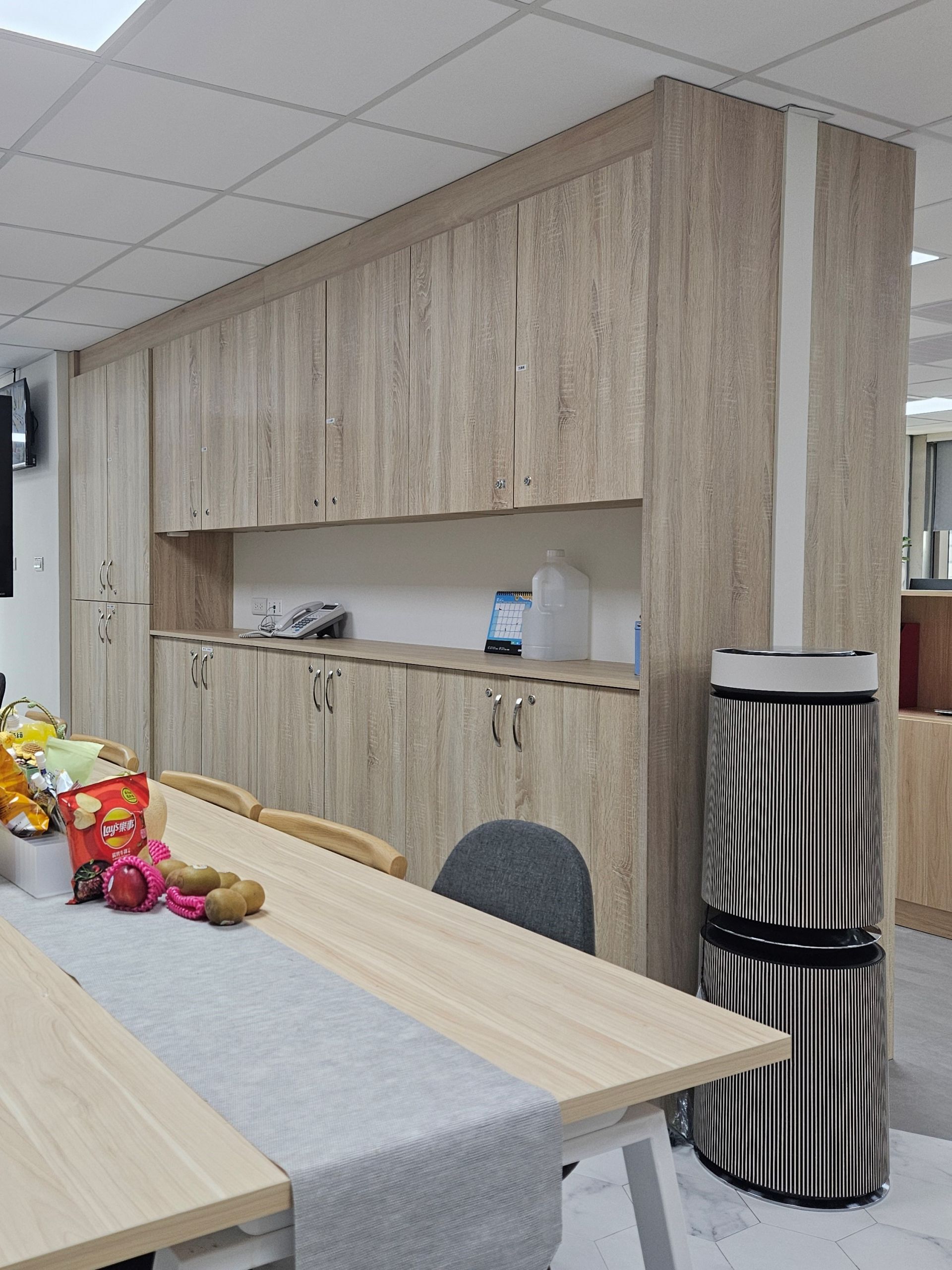 系統櫃設計高效收納，沿牆面設有大量木紋櫃體提供完善儲物機能保持環境整潔。