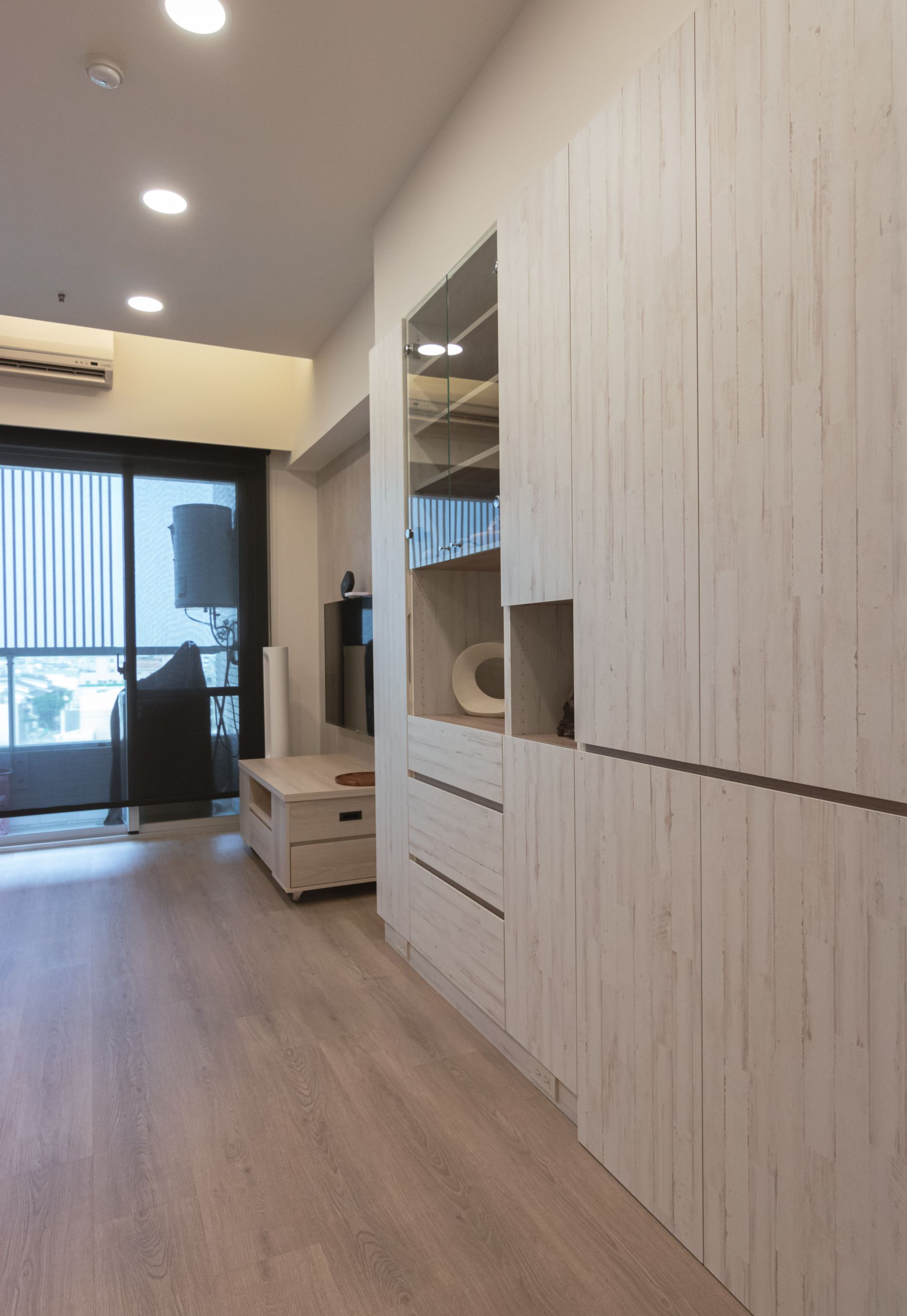 台南系統櫃設計。客廳系統高櫃，緩衝抽屜搭玻璃門片，高效收納保持空間整潔。